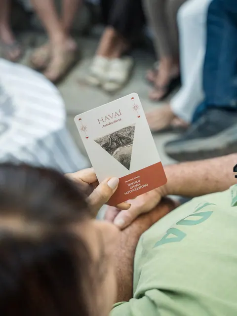 Mão segura uma carta com a palavra Havaí e o subtítulo Autodescoberta, na segunda edição do Lanú.Lab, na Chapada dos Veadeiros, em agosto de 2026.
