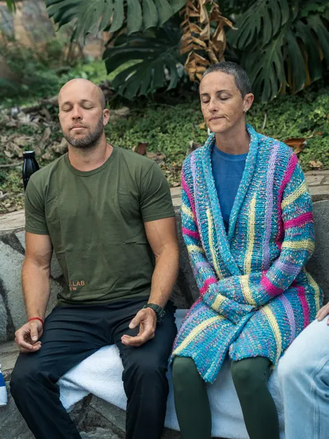 Homem e mulher sentados lado a lado, de olhos fechados, em um banco de pedra, na segunda edição do Lanú.Lab, na Chapada dos Veadeiros, em agosto de 2026.