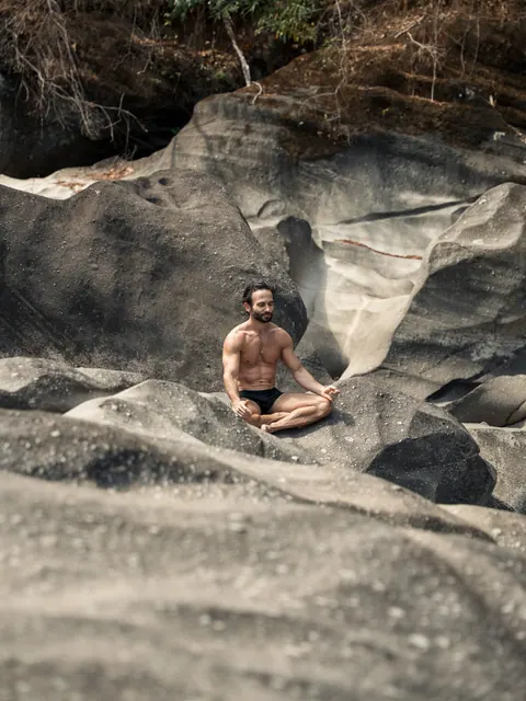 Homem sentado em posição de meditação sobre grandes rochas, na segunda edição do Lanú.Lab, na Chapada dos Veadeiros, em agosto de 2026.