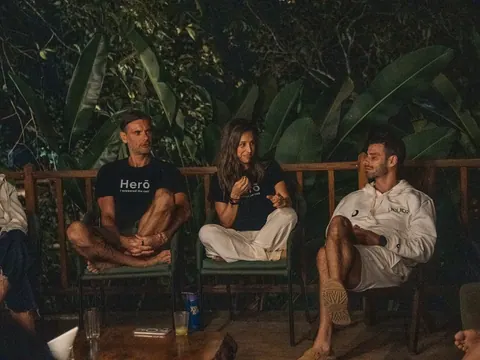 Três pessoas sentadas em cadeiras conversam à noite, com bananeiras ao fundo, na segunda edição do Lanú.Lab, na Chapada dos Veadeiros, em agosto de 2026.